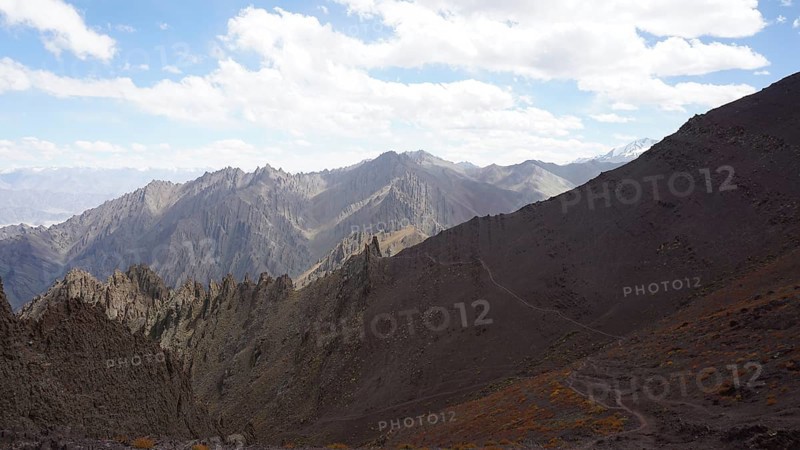 Rocky mountain range under cloudy sky and wide valley, trekking at Stok La Pass in Ladakh, Himalayas, India