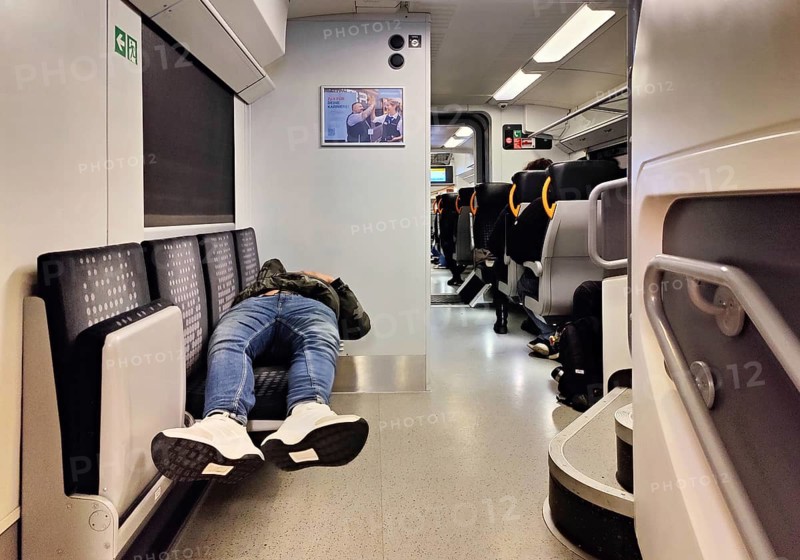 Sleeping man lying out early in the morning on the Wupper-Express RE 4 from National Express, Witten, North Rhine-Westphalia, Germany
