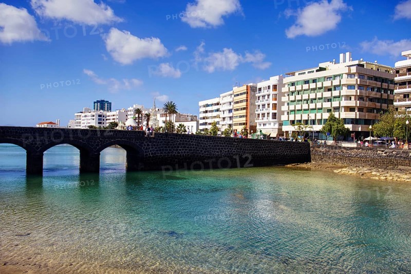 Historic bridge over clear water with modern buildings in the background under blue sky, Arrecife, Lanzarote, Canary Islands, Spain