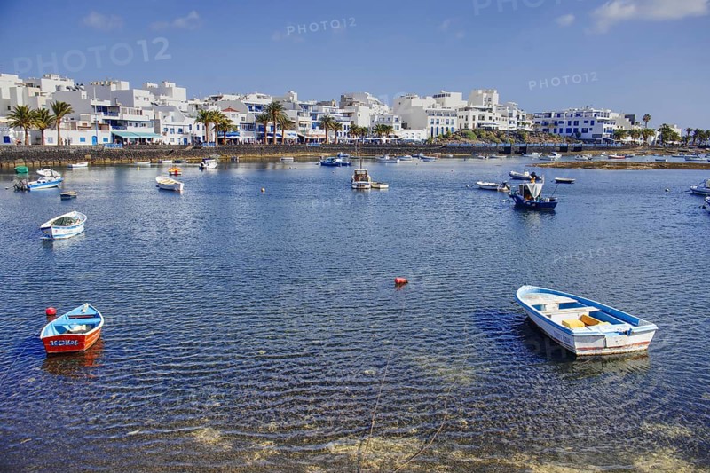 Coastal town with lagoon (Charco de San Ginés), scattered boats on calm water, white buildings on the horizon, Arrecife, Lanzarote, Canary Islands, Spain