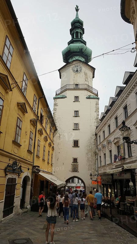 Historic old town street with a tower and people on the move, Bratislava, Slovakia