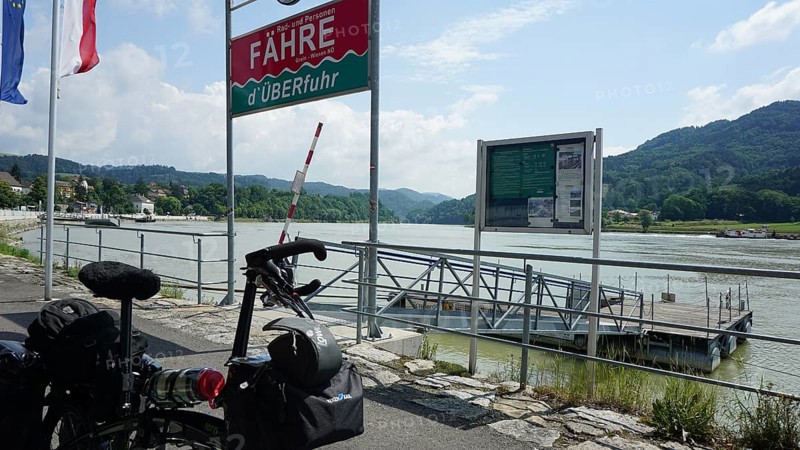 Cycling in front of a ferry with a view of the Danube and mountains, cycling on the Danube cycle path, Austria
