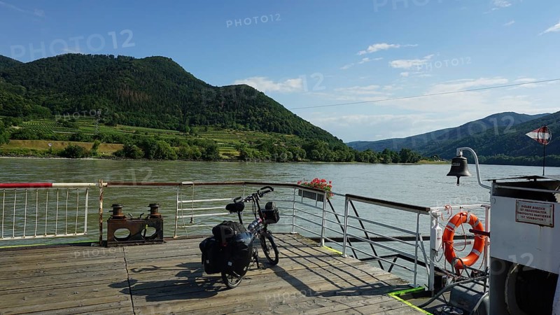 Ferry on the Danube with bicycle and mountains in the background, Danube cycle path, Austria