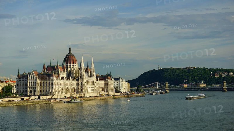 Large parliament building in Budapest on the banks of the Danube under blue sky with bridge in the background, Budapest, Hungary