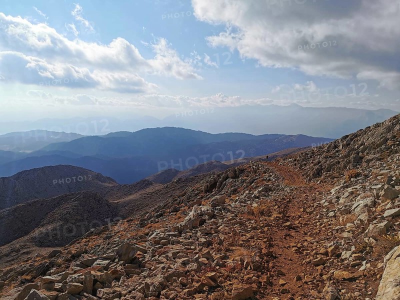 Rocky mountain trail with views of surrounding mountains and clouds, climbing Tahtali Dagi, Lycia, Turkey