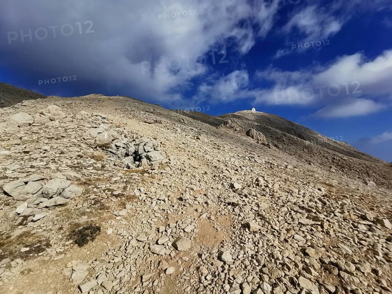 Rocky path leads to the summit of Tahtali Dagi under a partly cloudy sky, climbing Tahtali Dagi, Lycia, Turkey