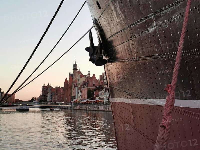 Looking along the bow, a large ship is moored in the harbor in front of the picturesque, historic city of Danzig in the evening light, Baltic Sea, Danzig, Poland