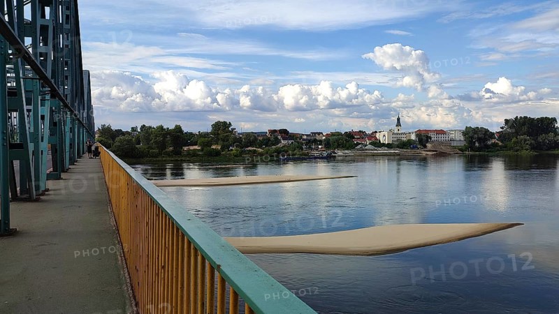 River landscape with two sandbanks in the Vistula with metal bridge, clouds and view of Torun city, Poland
