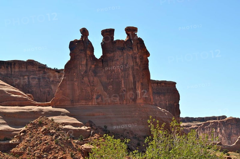 Three Gossips, a majestic red sandstone rock formation rising above a bright blue sky, Arches National Park, Utah, USA