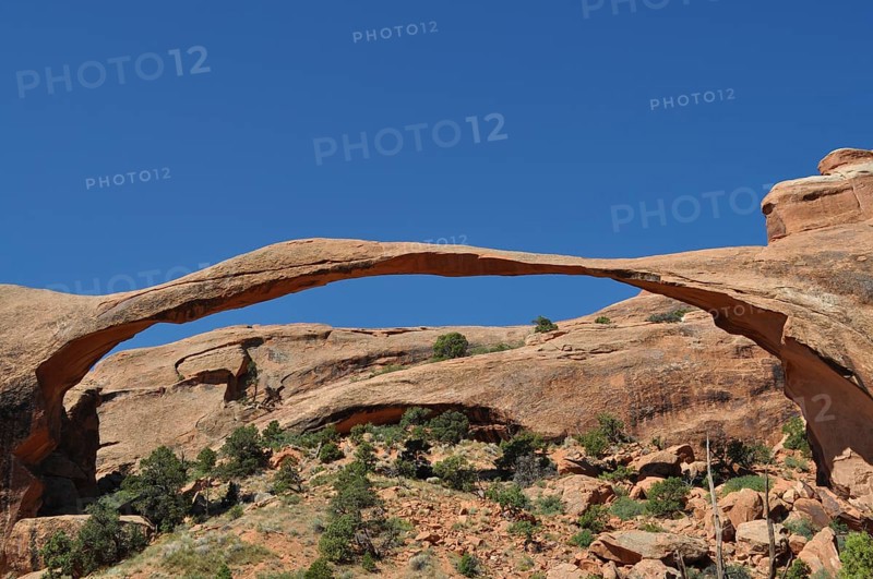 Landscape Arch, an impressive natural stone bridge against bright blue sky, Arches National Park, Utah, USA