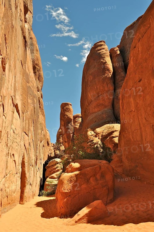 Narrow gorge surrounded by high rock walls with intense sunlight, Arches National Park, Utah, USA