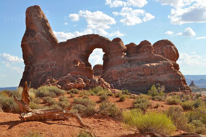 Turret Arch, a natural rock arch rising against a blue sky with scattered clouds in the red desert, Arches National Park, Utah, USA