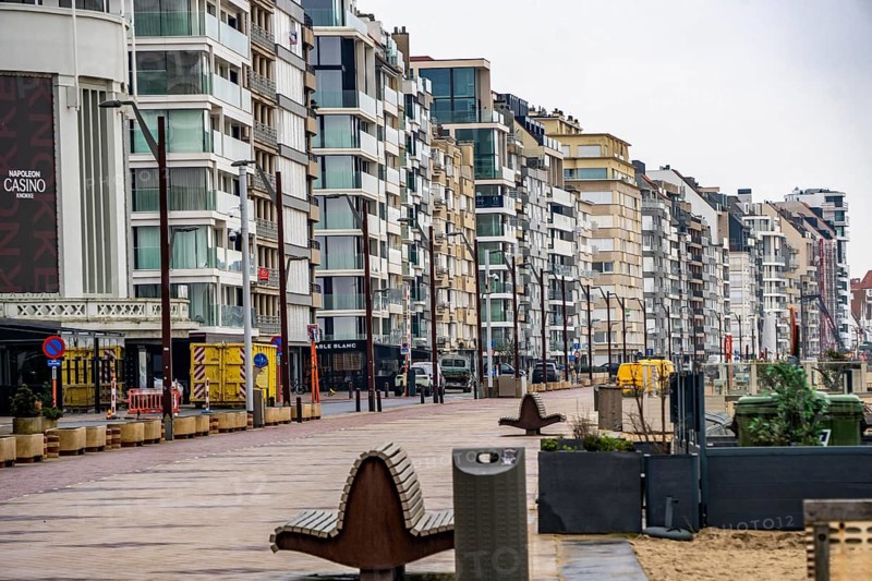 An urban promenade with modern high-rise buildings by the sea under cloudy sky, Zeedijk-Knokke, beach promenade in Knokke-Heist, on the North Sea beach, dreary winter day, mostly apartment buildings with rental or condominiums, high-rise buildings on the street, Belgium