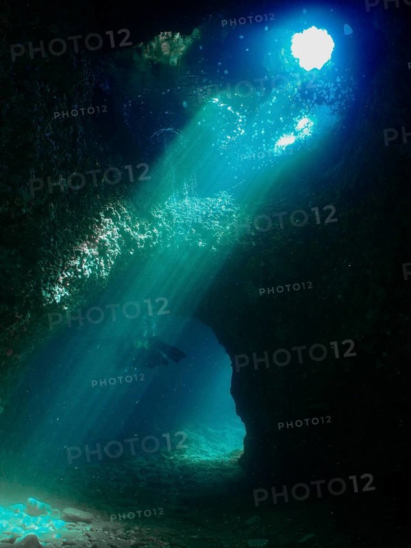 Rays of light illuminate the fascinating underwater cave that a diver explores. Fraskeric dive site, Stoja, Pula, Croatia, Mediterranean