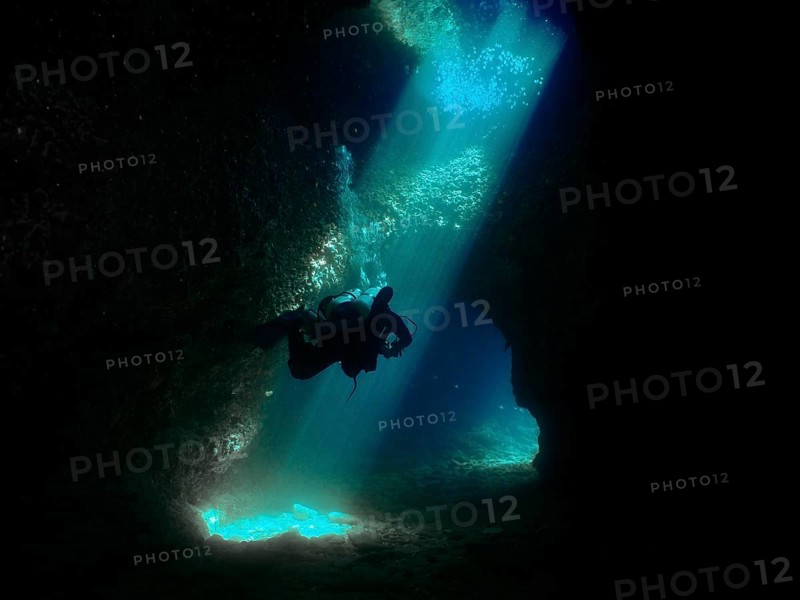 A diver floats through a mystical underwater cave, flooded with blue light. Fraskeric dive site, Stoja, Pula, Croatia, Mediterranean