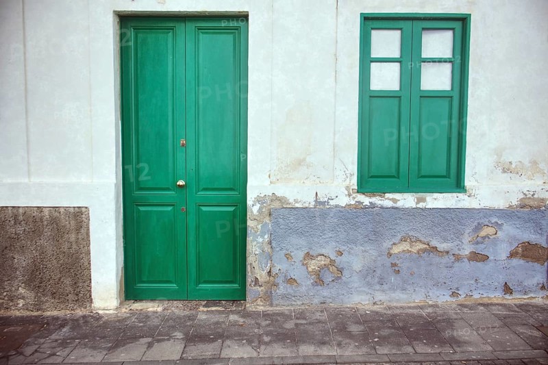Landscape close-up of a green door and window in Arrecife, Lanzarote. Speckled plaster gives the bright façade an authentic, slightly aged character, Arrecife, Lanzarote
