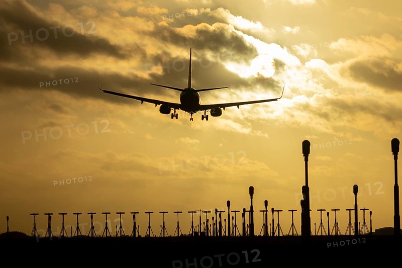 Boeing 737 commercial passenger airliner jet aircraft of Ryanair airways in flight on approach to land over runway lights at sunset at London Stansted airport, Essex, England, United Kingdom