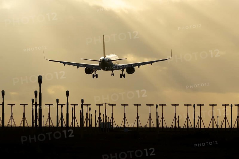 Airbus A321 commercial passenger airliner jet aircraft of Pegasus airlines flying on approach to land over runway lights at sunset at London Stansted airport, Essex, England, United Kingdom