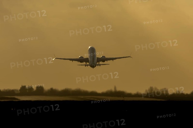 Airbus commercial passenger airliner jet aircraft taking off in flight silhouette at sunset at London Stansted airport, Essex, England, United Kingdom