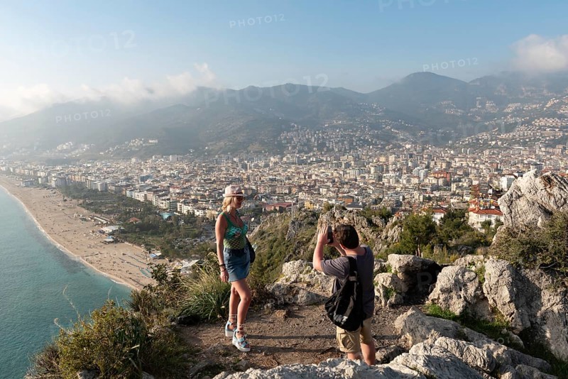Alanya, Turkey. April 7th 2021 Tourists posing for photographs on the mountain overlooking the city of Alanya and Kleopatra beach on the Mediterranean coast of Turkey