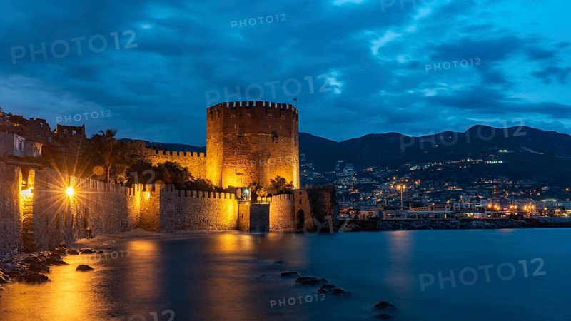 Alanya, Turkey, April 9th 2021 Stunning panorama of Alanya Harbour and the Red Tower at night with the Taurus Mountains and Mediterranean Sea, Turkey