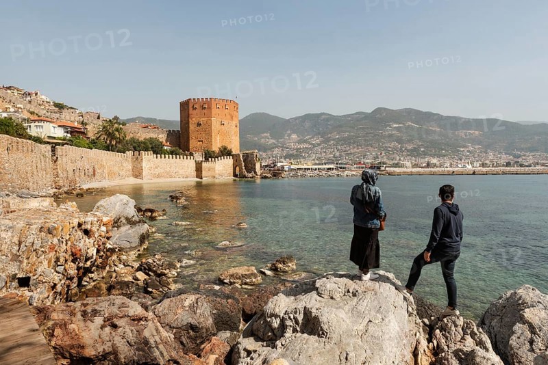 Alanya, Turkey. April 7th 2021 Turkish tourists enjoy the view of the ancient walls of Alanya castle and the Red Tower on the Mediterranean coast of Turkey