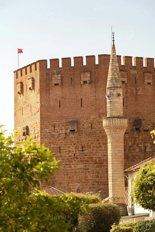 Alanya, Turkey. April 7th 2021 Mineret of Haci Kadiroglu Mosque in front of the famous Red Tower in Alanya harbour, southern Turkey