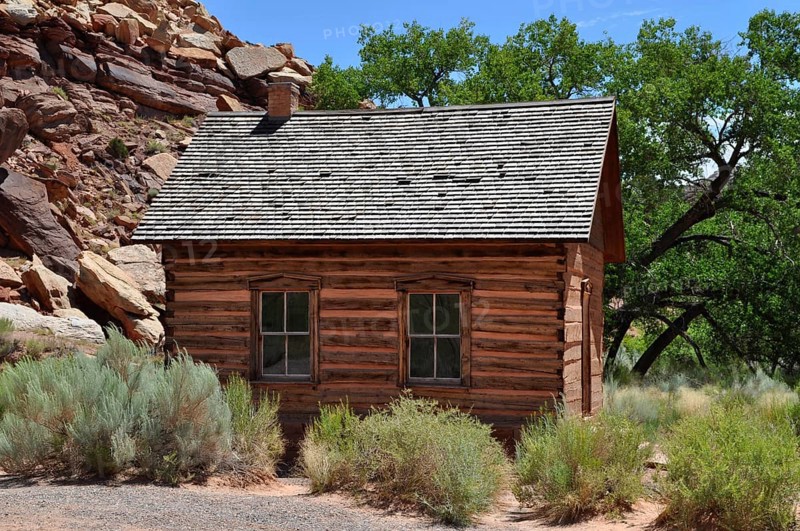 An old wooden cabin, old schoolhouse, between trees in a dry, summer landscape, Fruita, Capitol Reef National Park, Utha, USA