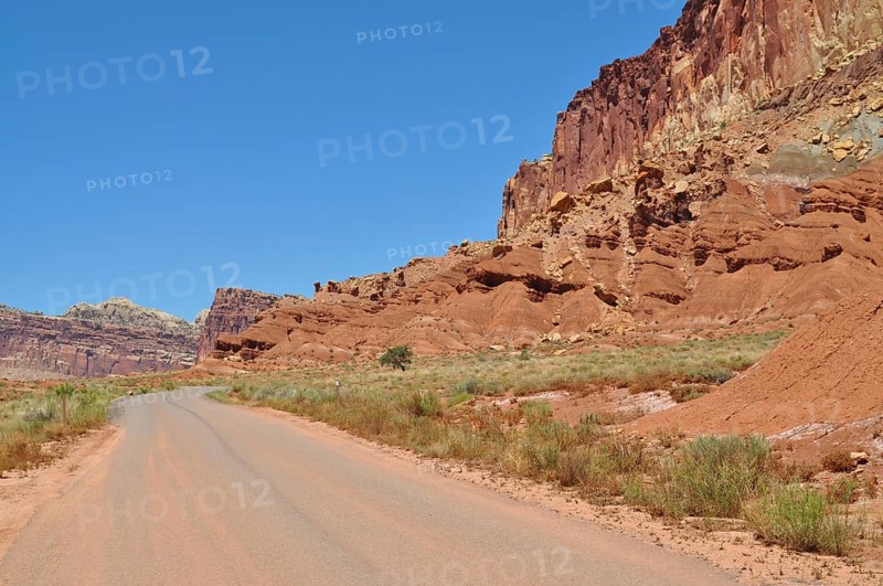 Deserted road through a wild red rock landscape under blue sky, Capitol Reef National Park, Utha, USA