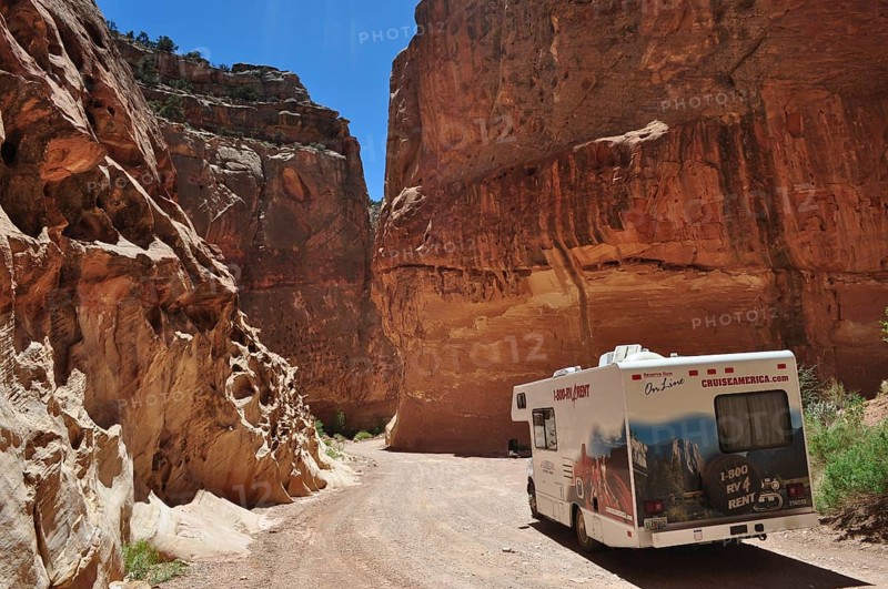 Motorhome traveling in a canyon with massive red rock structures under clear skies, Capitol Reef National Park, Utha, USA