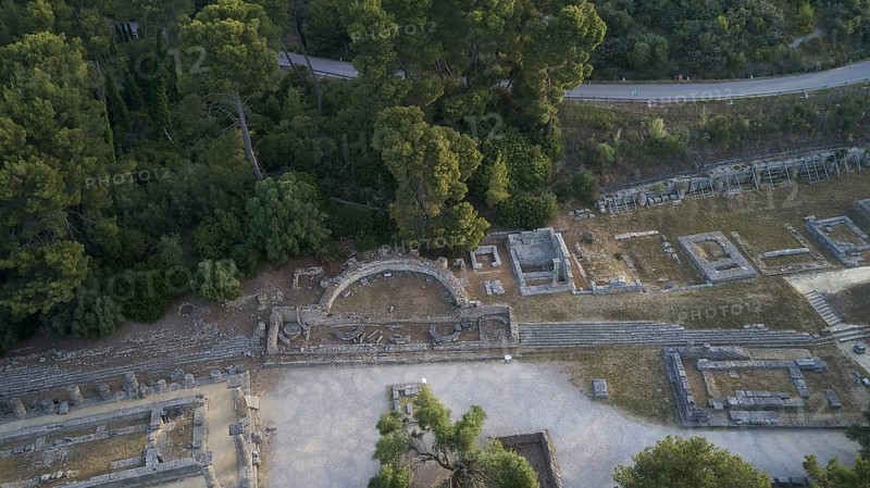 Soft morning light, Hera Temple, Old Theatre and surrounding ruins flanked by thick vegetation, drone shot, Archaeological Site, Ancient Olympia, Olympia, Peloponnese, Greece