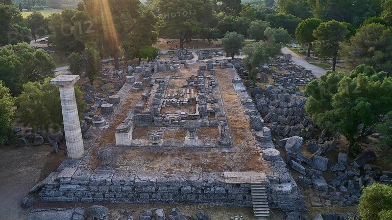 Temple of Zeus in backlight, ancient ruins surrounded by trees, with a stone column and archaeological structures, drone shot, archaeological site, Ancient Olympia, Olympia, Peloponnese, Greece