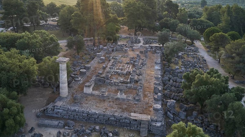 Temple of Zeus in backlight, architectural remains in a forest landscape with a visible stone column, drone shot, archaeological site, Ancient Olympia, Olympia, Peloponnese, Greece