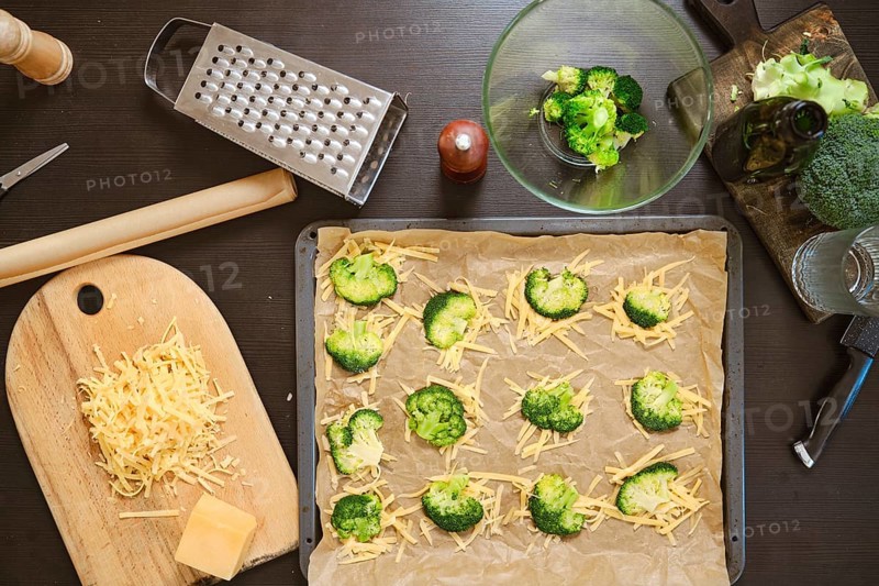 Overhead view of ingredients for smashed broccoli with cheese are on dark kitchen table
