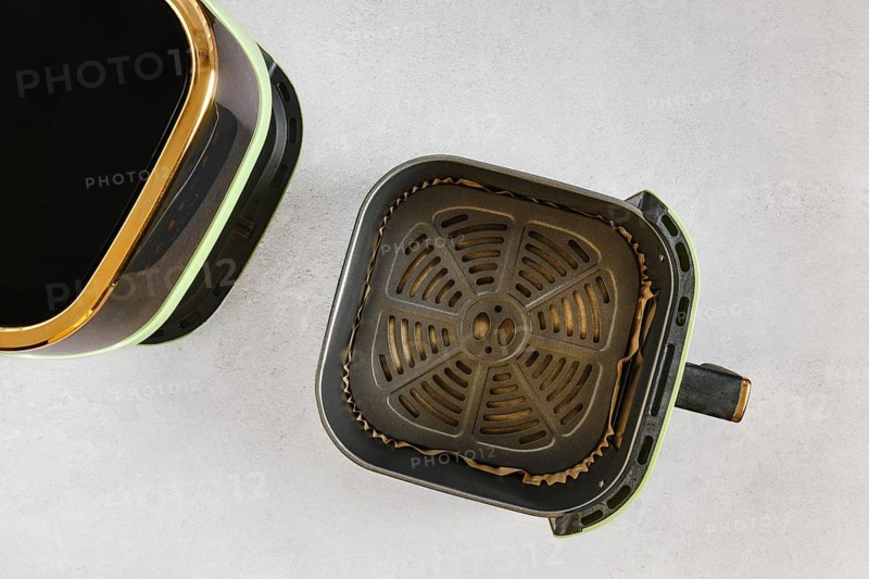 Top view of modern air fryer with empty basket lined with parchment paper, ready for quick healthy cooking in a contemporary home kitchen