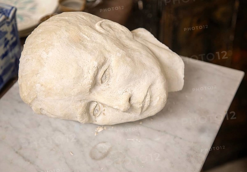 Human head and face plaster death mask or sculpture artwork on its side on marble, UK