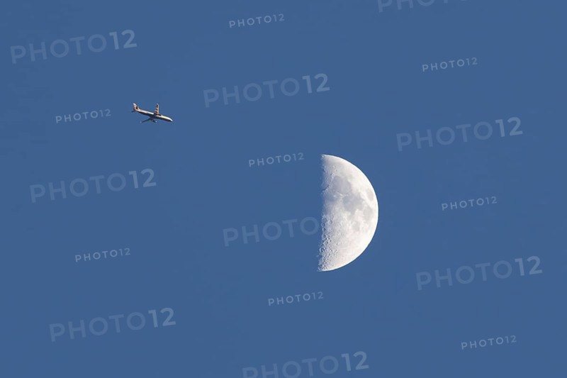 Airbus commercial passenger airliner jet aircraft of British airways in flight with the moon in the background, England, United Kingdom