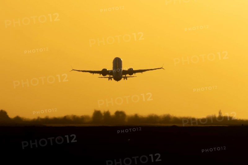 Airbus commercial passenger airliner jet aircraft taking off in flight silhouette at sunset at London Stansted airport, Essex, England, United Kingdom