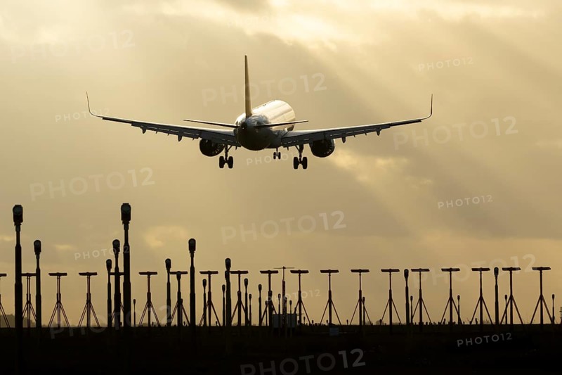 Airbus A321 commercial passenger airliner jet aircraft of Pegasus airlines flying on approach to land over runway lights at sunset at London Stansted airport, Essex, England, United Kingdom