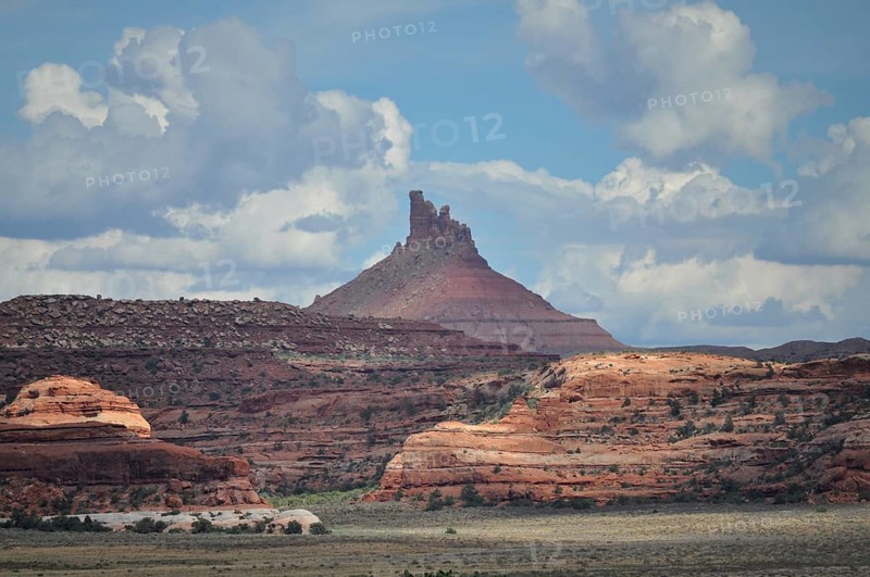 Distinctive pointed rock rises high, surrounded by red rocks and dramatic cloud formations, Canyonlands National Park, Utah, USA