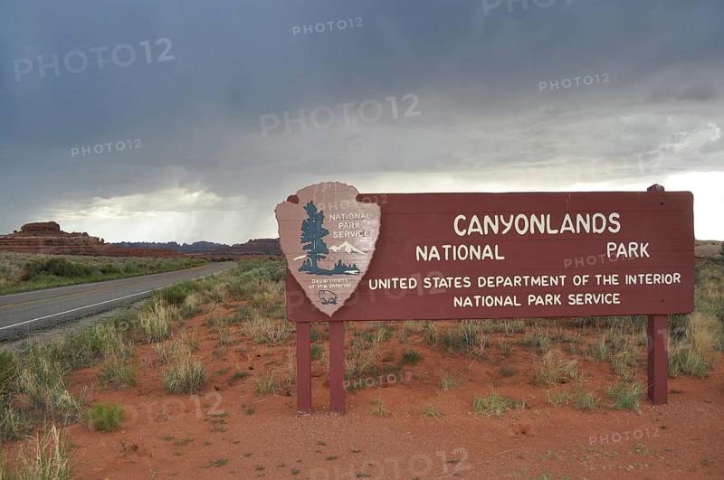Canyonlands National Park entrance sign under cloudy sky in a dry desert landscape, Canyonlands National Park, Utah, USA