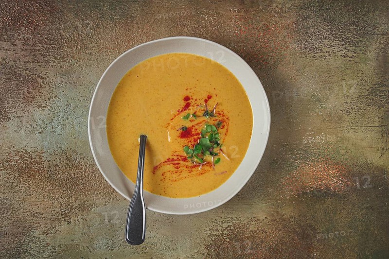 Pumpkin cream soup, in a white bowl on a textured background, top view, homemade, no people, rustic style