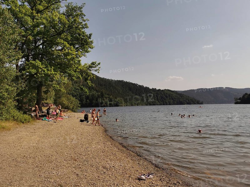 Bathers relax on a pebble beach on a quiet lake, Hohenwarte Reservoir, Thuringian Forest nature park Park