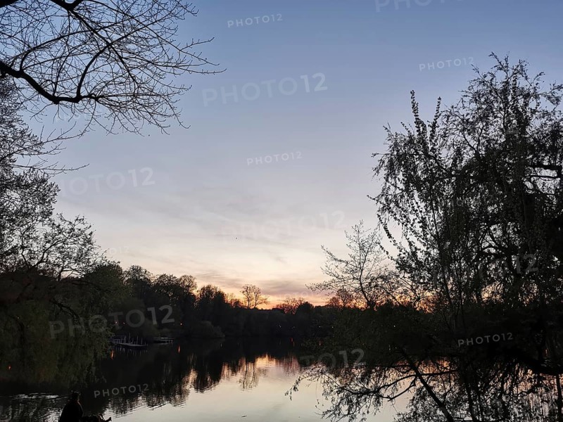 The sunset is reflected in a lake surrounded by trees, Franconian Forest nature park Park