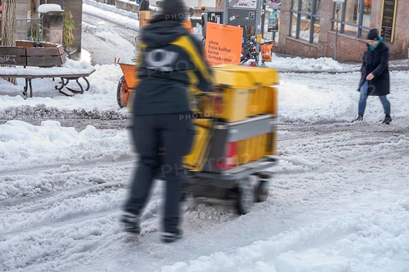 Movement, postman walking with loaded handcart on wintry roads in the city, Nuremberg, Middle Franconia, Bavaria, Germany