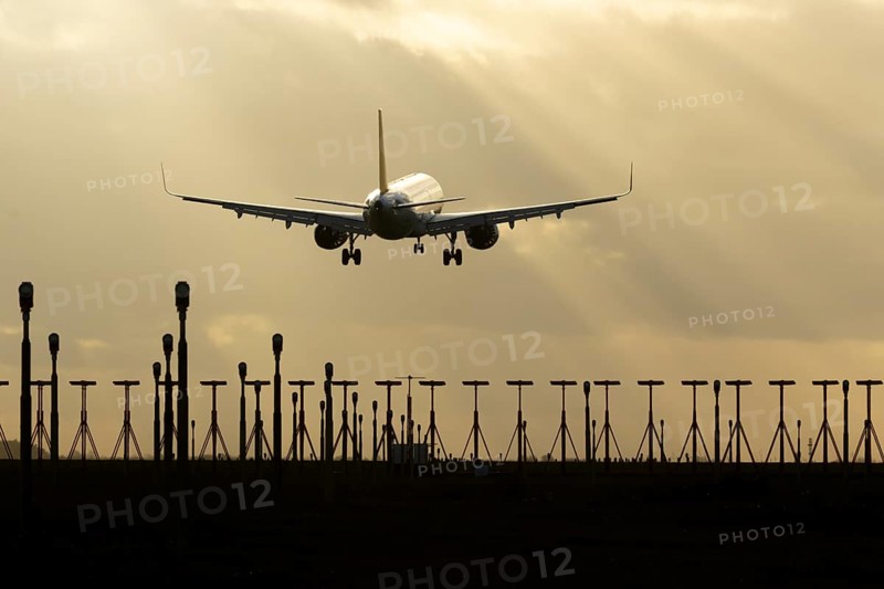 Airbus A321 commercial passenger airliner jet aircraft of Pegasus airlines flying on approach to land over runway lights at sunset at London Stansted airport, Essex, England, United Kingdom