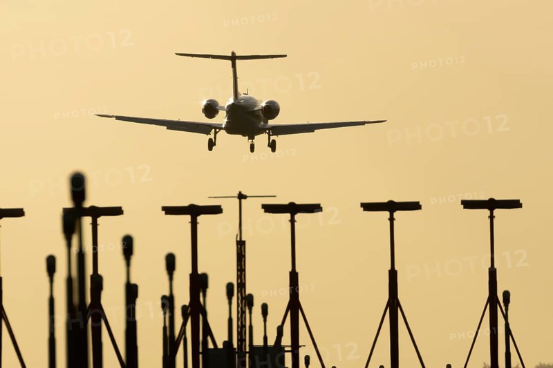 Cessna Citation small executive business jet aircraft in flight on approach to land over runway lights at sunset at London Stansted airport, Essex, England, United Kingdom