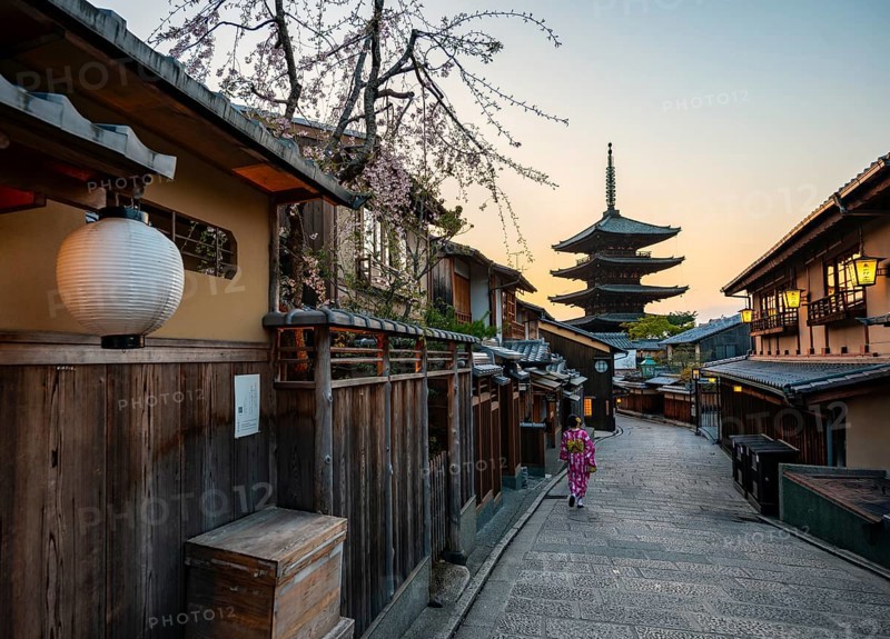 Japanese woman in kimono in an alley, Yasaka dori historic alleyway in the old town with traditional Japanese houses, five-story Yasaka Pagoda of the Buddhist Hokanji Temple in the back, evening mood, sunset, Higashiyama, Kyoto, Japan