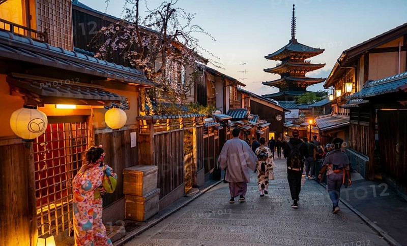 Japanese woman and men wearing kimono in an alley, Yasaka dori historic alleyway in the old town with traditional Japanese houses, five-story Yasaka pagoda of the Buddhist Hokanji Temple, evening mood, Kyoto, Japan