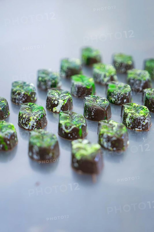 Fully decorated chocolates with green decoration on a surface, vegan chocolates production, Haselstaller Hof, Gechingen, Germany